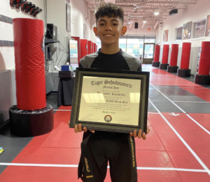 Boy holding his black belt certificate at Tiger Schulmann's Rockville