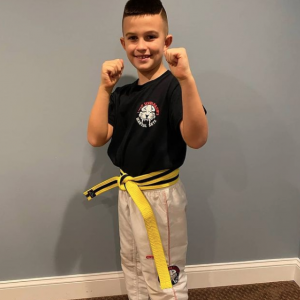 A boy in fighting stance smiling at home in Smithtown