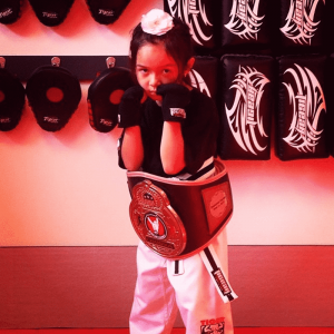 A little girl in fighting stance with championship belt
