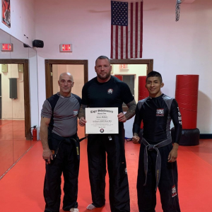 Three martial arts fighters showing a certificate from Tiger Schulmann's