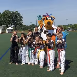 A group of kids and their instructors and a mascot on the field