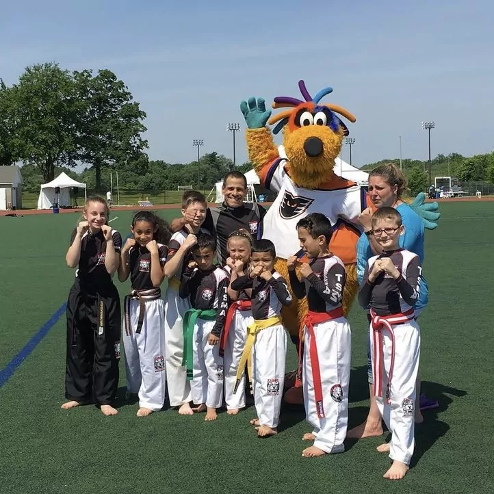 A group of kids and their instructors and a mascot on the field