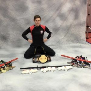 A female martial arts fighter sitting on her knees with numerous medals in front of her