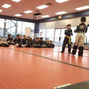 Two boys sparring while other kids watching