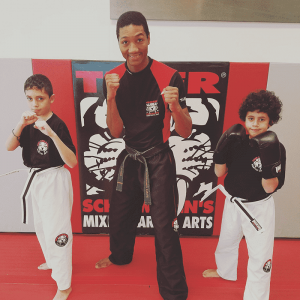 Instructor and two boys with fists up