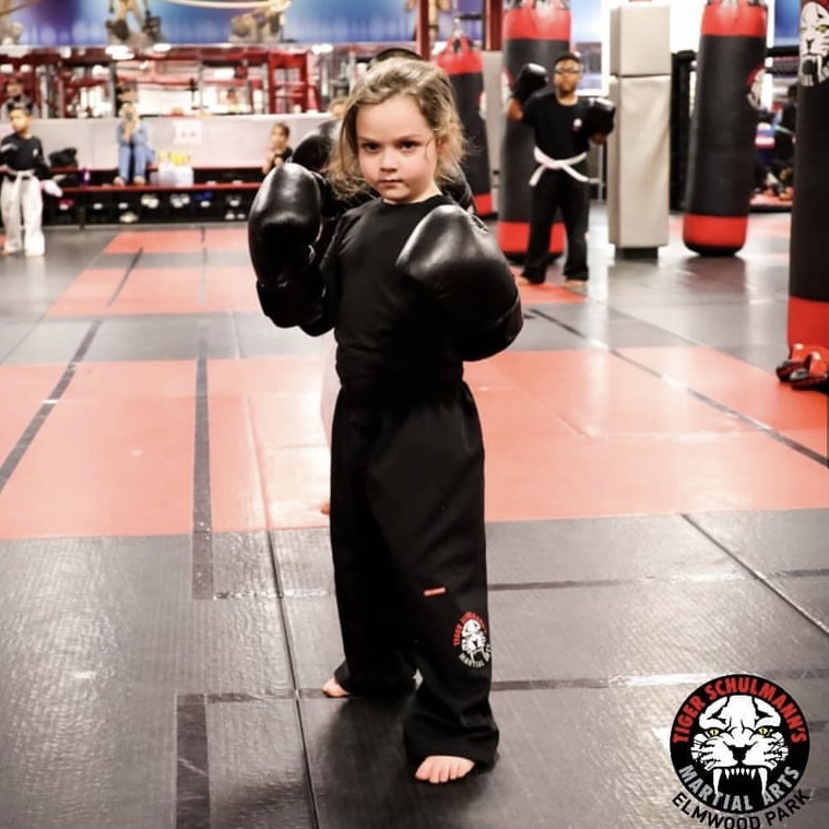 A little girl in a boxing stance at Tiger Schulmann's