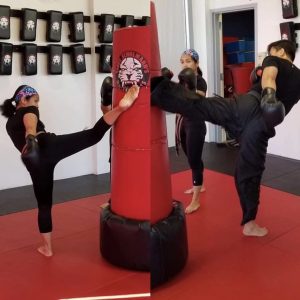 Two girls and a man kicking a red punching bag
