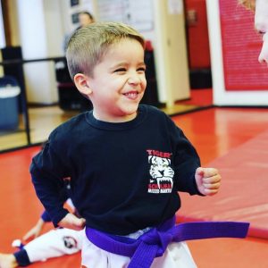 A boy smiling in karate stance at Tiger Schulmann's in Hoboken