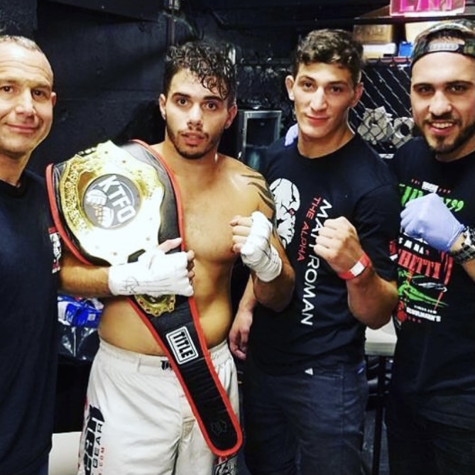 Martial arts fighter with championship belt and his team members