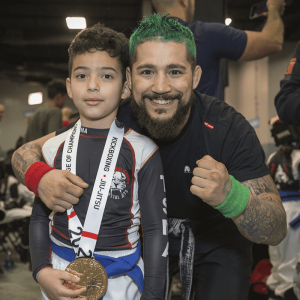 A boy with a medal and his instructor at Tiger Schulmann's