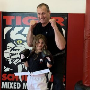 Sensei with young girl smiling with their fists raised at Tiger Schulmann's