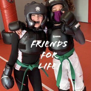 Two girls in martial arts gear hugging