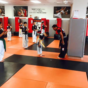 A boy and his instructor bowing with other kids clapping