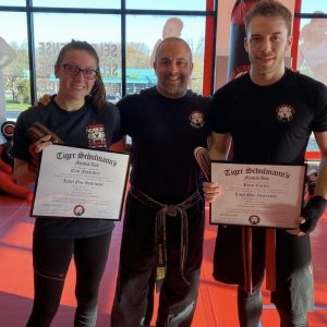 Two men and a woman posing with martial arts certificates