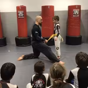 Martial arts instructor and a boy performing exercises while others observing