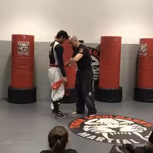 Two martial arts fighters on a training in front of punching bags