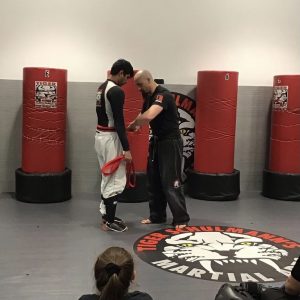 Two martial arts fighters on a training in front of punching bags