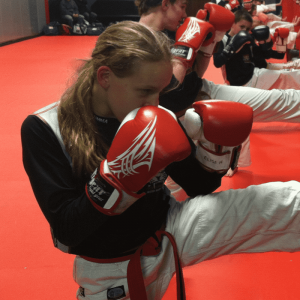 A girl in a kickboxing training with other kids