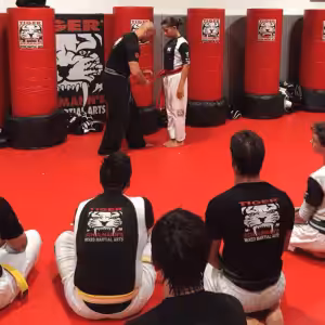 Instructor and a girl exercising while other kids sit and watch