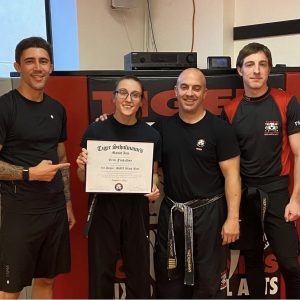 A girl showing martial arts certificate with her instructors