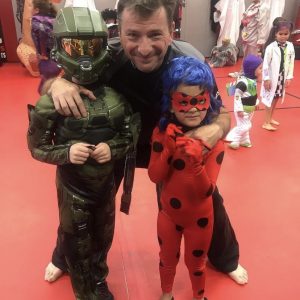 Martial arts instructor with two kids dressed in Halloween costumes