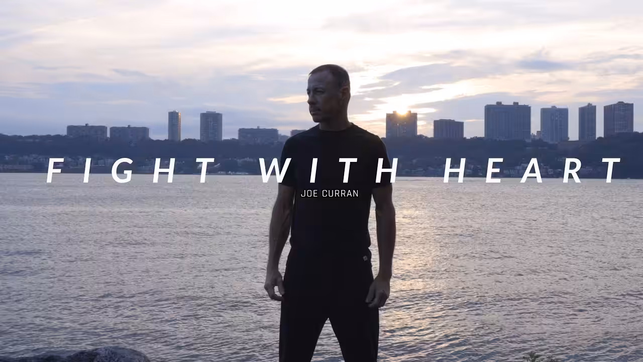 Man standing in front of a cityscape with FIGHT WITH HEART letters