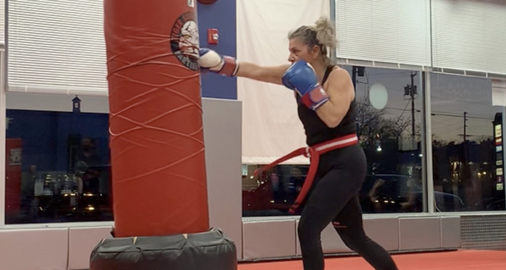 Kim Lupo punching a red bag during kickboxing class at Tiger Schulmann's