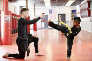 A boy practices kicking with his martial arts instructor at Tiger Schulmann's