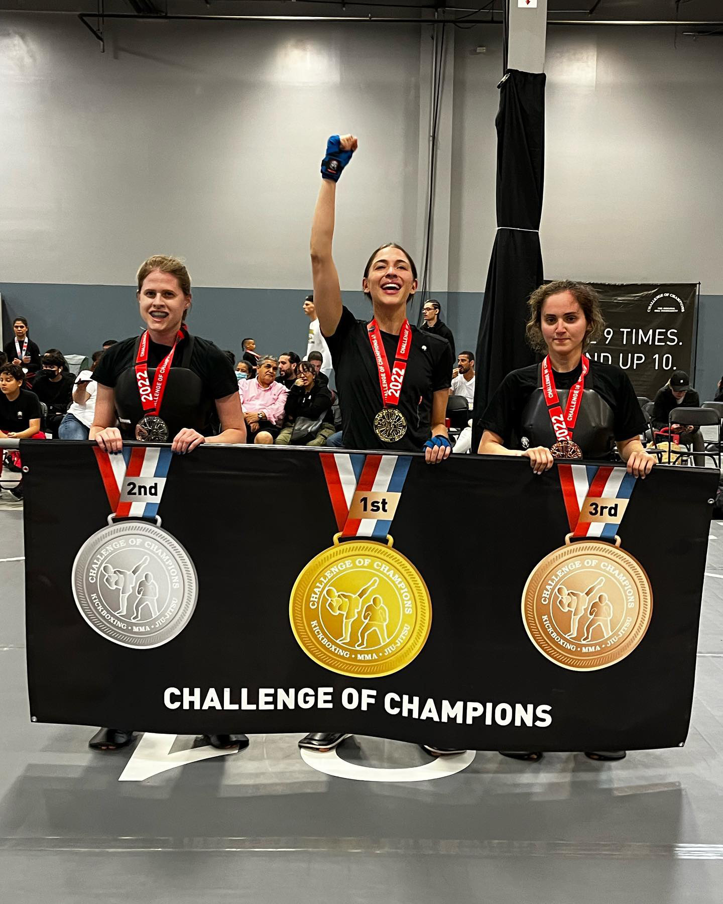Three girls Tiger Schulmann's martial arts fighters holding Challenge of Champions winning banner