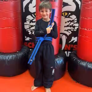 A boy proudly showing his martial arts blue belt at Tiger Schulmann's Eatontown
