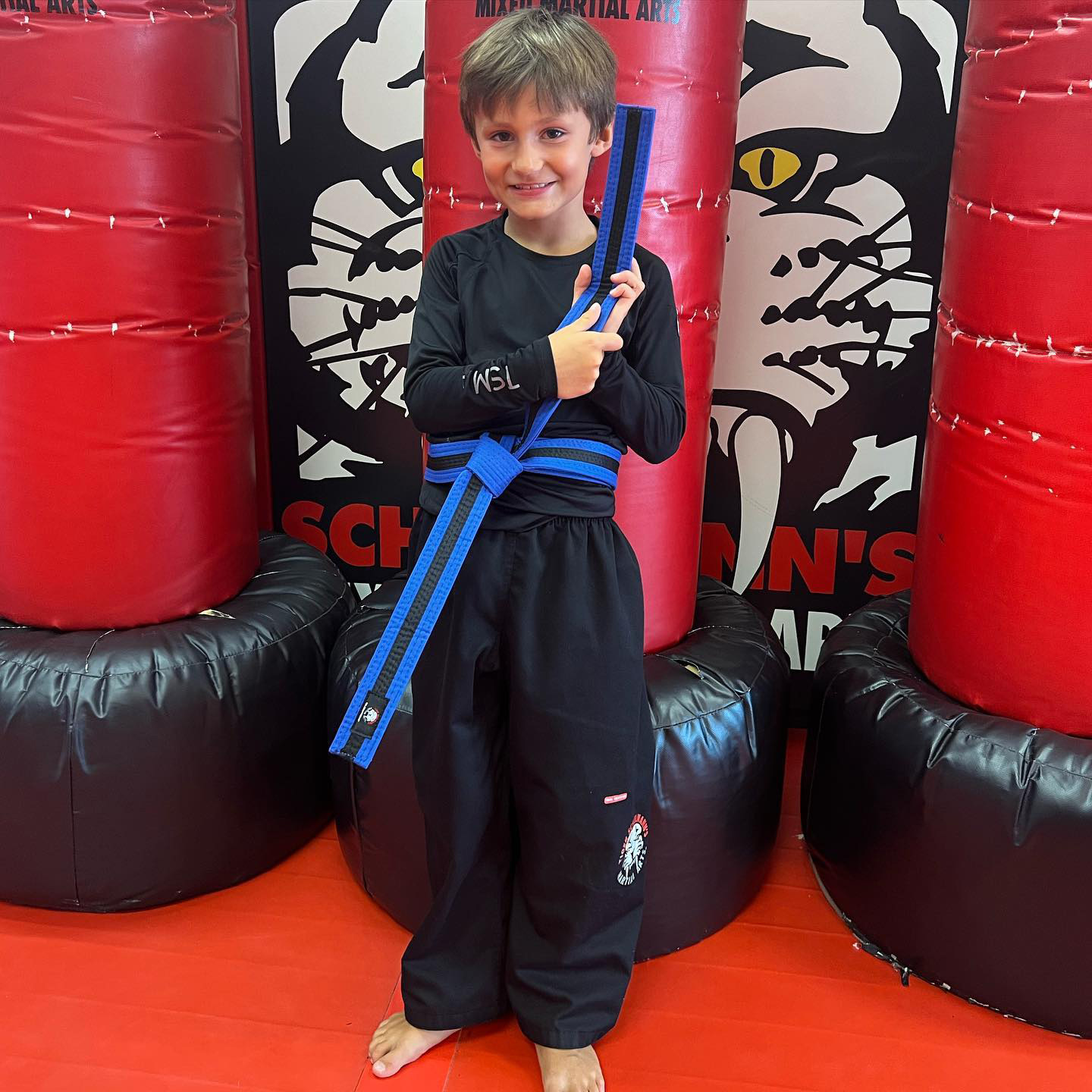 A boy proudly showing his martial arts blue belt at Tiger Schulmann's Eatontown