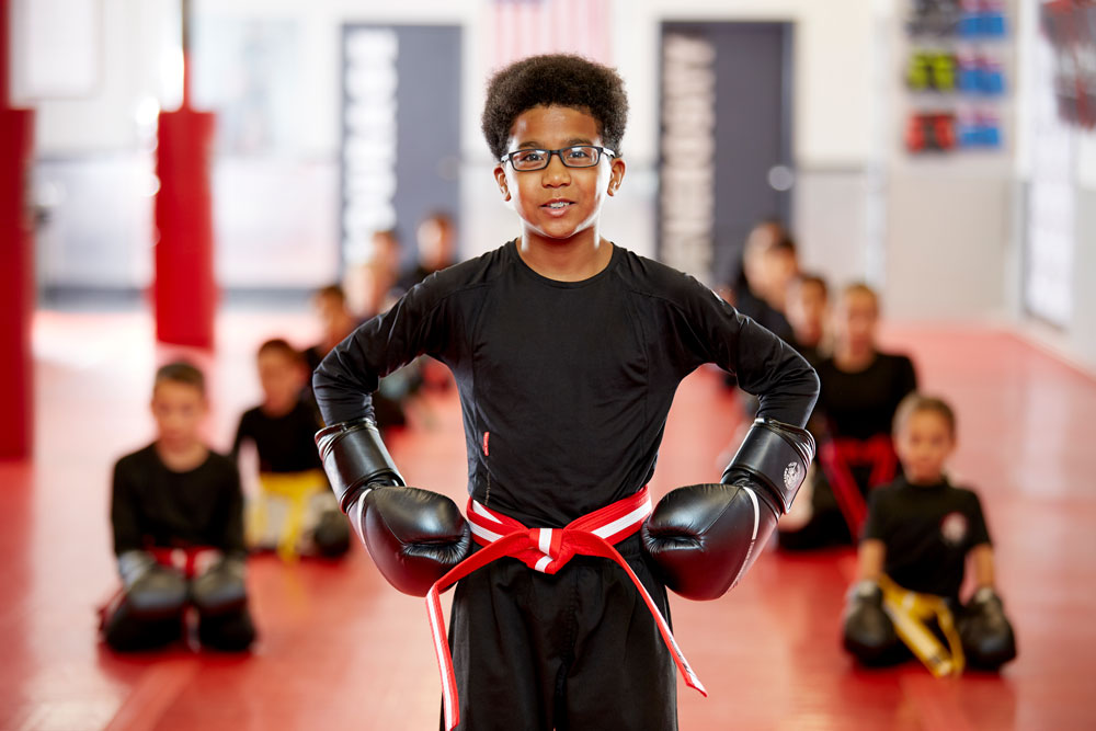 Kid in gloves standing in front of martial arts class