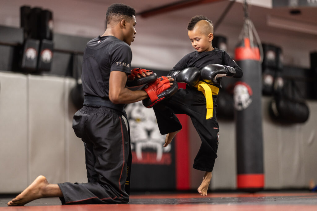Kid practicing knee kick with his instructor