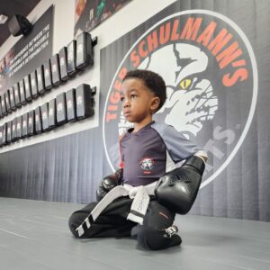 Little boy sitting on his knees wearing kickboxing gloves at Tiger Schulmann's Martial Arts in Horsham, PA