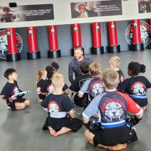 Kids sitting on a mat around Sensei during the martial arts training at TSMA Horsham