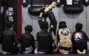 Five kids sitting and watching Instructor performing Jiu-Jitsu moves at Tiger Schulmann's Martial Arts